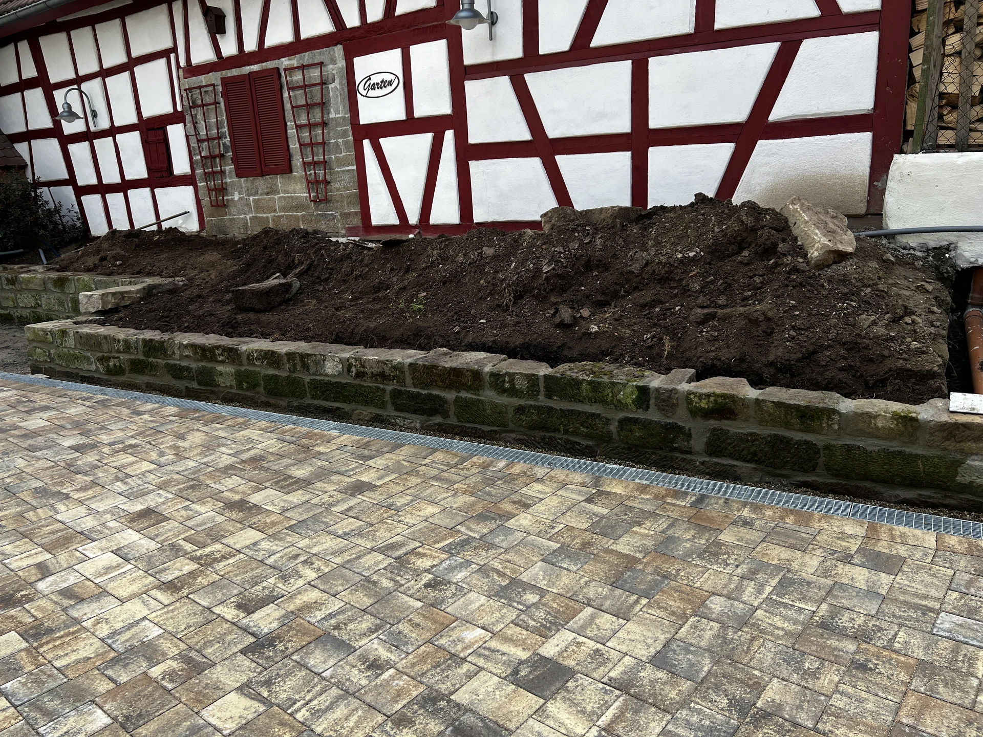 Wiederaufgebaute Sandsteinmauer mit vorbereitetem Beet